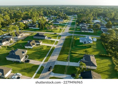 Aerial view of street traffic with driving cars in small town. American suburban landscape with private homes between green palm trees in Florida quiet residential area - Powered by Shutterstock