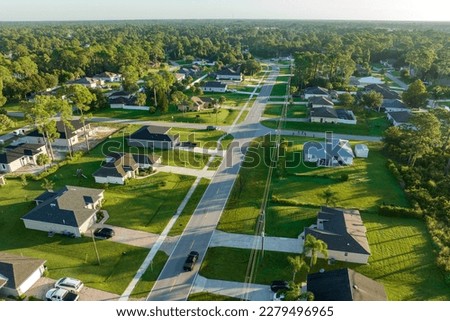 Aerial view of street traffic with driving cars in small town. American suburban landscape with private homes between green palm trees in Florida quiet residential area
