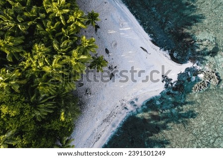 An aerial view of a stunning beach on the island of Guam, with an expansive shoreline and clear blue water