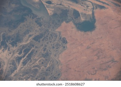 Aerial view of a stunning mountain range with snowcapped peaks and dramatic rock formations. The landscape is characterized by rugged terrain and intrica. Elements of this image furnished by NASA - Powered by Shutterstock