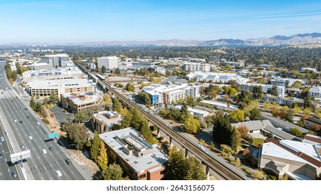Aerial view of a suburban city landscape with highways and railway, urban infrastructure and residential areas under clear blue sky, transportation and city planning development concept
