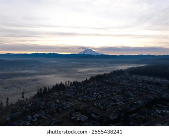 Aerial view of a suburban neighborhood with Mount Rainier in the background at sunrise, featuring misty fields, soft light, and a serene atmosphere. - Powered by Shutterstock