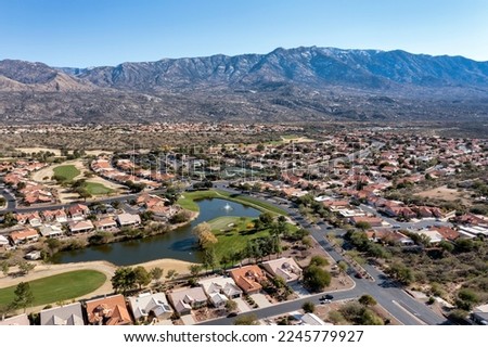 Aerial view of a suburban residential community with a golf course and tennis courts in a desert environment with the Catalina Mountains in the background near Tucson, Arizona.