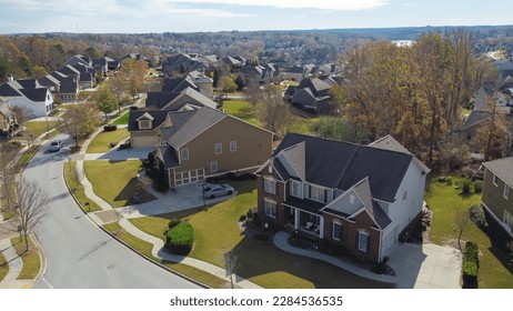 Aerial view suburban residential street with row of upscale two-story new development houses and master planned community in distance background outside Atlanta, Georgia, USA. Large homes grassy lawn