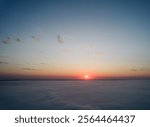 Aerial view of sun rises above dense clouds, casting warm, golden glow across horizon. Scene captures tranquility of new day, as the first rays of sunlight break through, creating serene atmosphere.