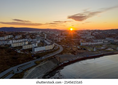 Aerial view of sunrise over the coastal city. Morning top view of the streets and buildings. City of Magadan, Magadan region, Siberia, Far East of Russia.