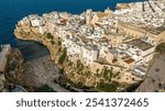 Aerial view at sunset of the historic center of Polignano a Mare, in the province of Bari, Puglia, Italy. On the left is Lama Monachile beach, the most important and famous beach in town.