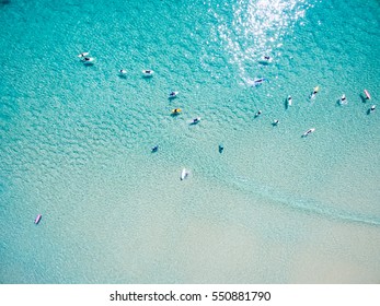 An aerial view of surfers waiting for a wave in the ocean on a clear day