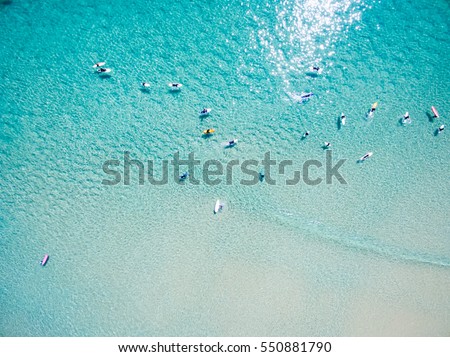 An aerial view of surfers waiting for a wave in the ocean on a clear day