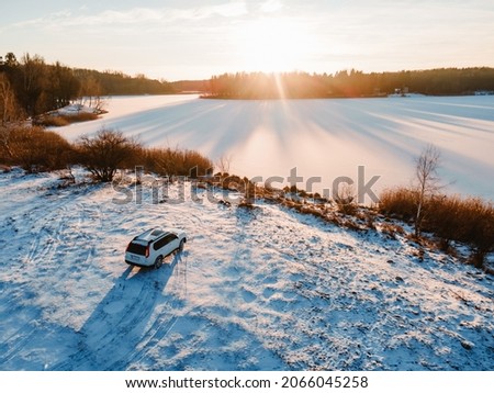 aerial view of the suv car at the beach of frozen lake on sunset copy space
