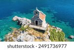 Aerial view of the Sveta Neđelja islet and its small hilltop church off the coast of Petrovac na Moru, a resort town by the Adriatic Sea in Montenegro