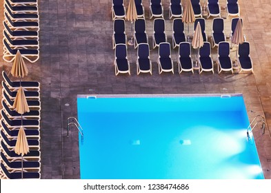 Aerial View Of A Swimming Pool And Deck Chairs At Night.