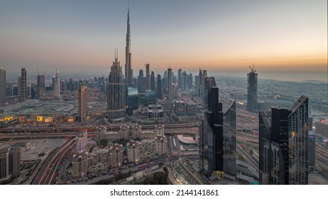 Aerial view of tallest towers in Dubai Downtown skyline and highway day to night transition timelapse. Financial district and business area in smart urban city. Skyscraper and high-rise buildings