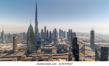 Aerial view of tallest towers in Dubai Downtown skyline and highway timelapse during all day. Skyscraper and high-rise buildings with shadows moving fast