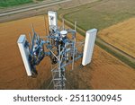 Aerial view of a telecom cell tower antennas and radios view form top over a rural field. Drone view of a self support cell tower top.