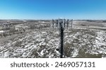 Aerial view of a telecom self support cell tower antennas in rural area in spring. Drone closeup view of a guyed cell tower top, scenic view late spring, snow.