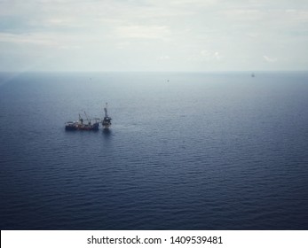 Aerial View of Tender Drilling Oil Rig (Barge Oil Rig) in The Middle of The Ocean or gulf, Offshore tender rig barge with crane and cable . Derrick of tender, remote platform, oil and gas industry