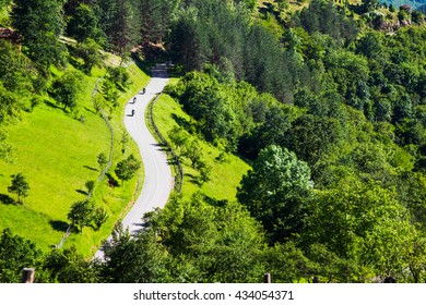 Aerial view of three motorcyclists on a winding rural road through a scenic lush green forested mountain valley - Powered by Shutterstock