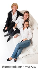 Aerial View Of Three Smiling Women Of Different Ages On A White Sofa