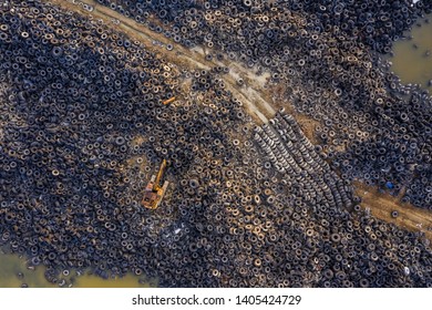 Aerial view of tire landfill. Environmental disaster. Yellow old excavator.