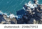 Aerial view Top down seashore. Waves crashing on rock cliff.