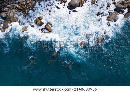 Aerial view Top down seashore big wave crashing on rock cliff Beautiful blue sea surface in sunny day summer background Amazing seascape top view seacoast at Phuket Thailand