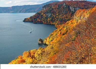 Aerial view of a tour boat cruising on magnificent Towada Lake (十和田湖) in autumn season, in Towada Hachimantai National Park, Aomori, Japan. Breathtaking scenery of grand nature in Northeastern Japan