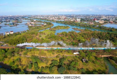 Aerial view of a tourist train, hauled by a vintage steam locomotive, traveling on a sunny day thru lush forests and wetlands in Eco Ark Riverside Park next to Dongshan River in Luodong, Yilan, Taiwan - Powered by Shutterstock