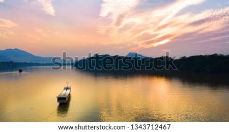 Aerial view of a tourists boat sailing along the Mekong river at sunset. Sunset Cruise is a slow-boat cruise along the Mekong river and is one of the most famous tourist attractions of Luang Prabang.
