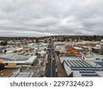 An aerial view of the town of Armidale with buildings and traffic on roads under a gray cloudy sky