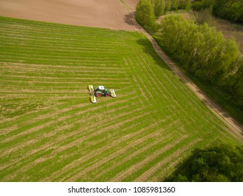 Aerial view of a tractor mowing a green fresh grass field, 
a farmer in a modern tractor mowing a green fresh grass field on a sunny day - Shutterstock ID 1085981360