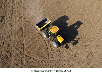 aerial view of a tractor and its shadow with a fertilizer seeder