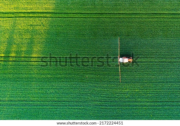 Aerial view of a tractor spraying\
agricultural fields. spraying herbicides on the\
field