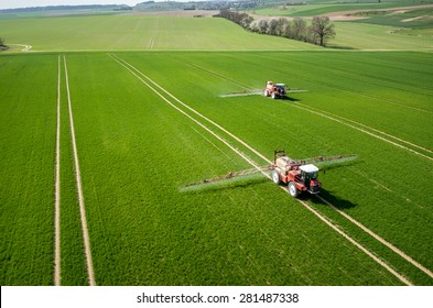 Aerial view of the tractor spraying the chemicals on the large green field