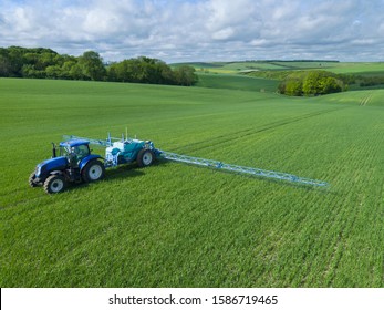 Aerial View Of Tractor Spraying Crop In Green Farm Fields With Pesticide