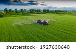 Aerial view of a tractor that irrigates the field with a young, fresh potato at sunset. The process of spraying field growths from insects and loaders.