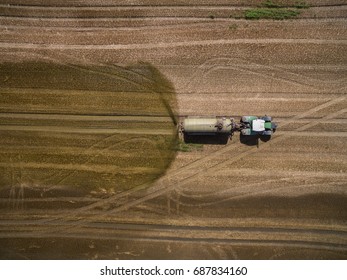 aerial view of a tractor with a trailer fertilizes a freshly plowed agriculural field with manure in germany
