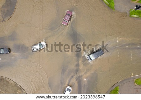 Aerial view of traffic cars driving on flooded road with rain water.