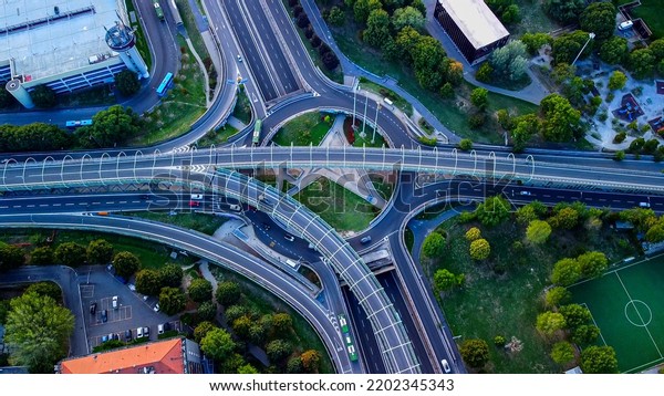 Aerial view of the traffic circle and exit from\
the freeway. Crossroads. Transport. Bus. Car. Motorbike. Asphalt.\
Traffic. Italy Milan\
09.2022\
