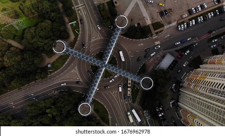 Aerial view of traffic on roundabout with nice architecture pedestrian crosswalk above intersection look like cross spinning counterclockwise