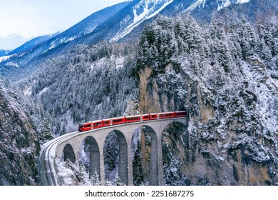 Aerial view of Train passing through famous mountain in Filisur, Switzerland. Landwasser Viaduct world heritage with train express in Swiss Alps snow winter scenery.  - Shutterstock ID 2251687275