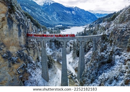 Aerial view of Train passing through famous mountain in Filisur, Switzerland. Landwasser Viaduct world heritage with train express in Swiss Alps snow winter scenery. 