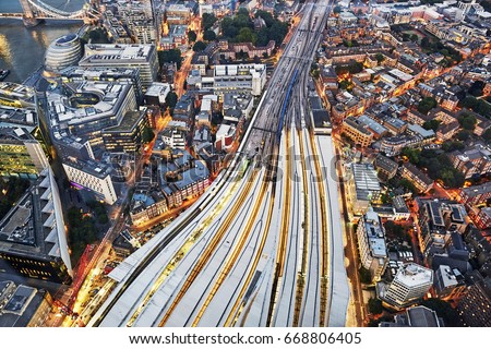 Aerial view of train tracks entering London Bridge illuminated at dusk 