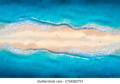 Aerial view of transparent blue sea with waves on the both sides and people on sandy beach at sunset. Summer travel in Zanzibar, Africa. Tropical landscape with lagoon, white sand and ocean. Top view - Powered by Shutterstock