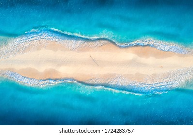 Aerial View Of Transparent Blue Sea With Waves On The Both Sides And People On Sandy Beach At Sunset. Summer Travel In Zanzibar, Africa. Tropical Landscape With Lagoon, White Sand And Ocean. Top View