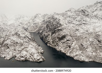 Aerial view of Trollfjord with snow-capped mountains on Lofoten Islands, Nordland, Norway. Typical cloudy weather with mountains in fog. Misty place.