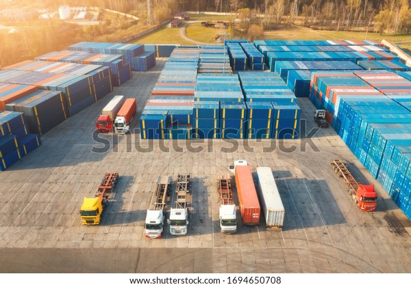Aerial view of trucks and containers at sunset. \
Top view of autotrucks, container warehouse in logistics terminal\
for export and import. Business. Freight transportation. Shipping\
and cargo. Industry