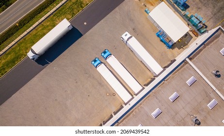 Aerial View Of Trucks Loading In The Distribution Hub. Logistics Center In Industrial City Zone From Top Down View. Background Texture Concept.