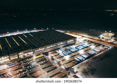 Aerial view of the trucks unloading at the logistic center. Night view with a bit of snow.