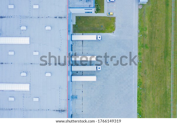 Aerial view of trucks unloading in\
logostics center. Logistics center in industrial city zone from\
above. Aerial view of trucks loading at logistic\
center